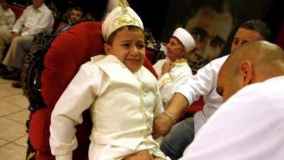 menino sendo submetido a circuncisao por religioso muçulmano